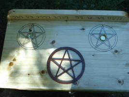 Two Candle Holders surrounded by wood-burned pentacles, and A Mounted Scrolled Pentagram in circle centered on table top of this Wooden Altar